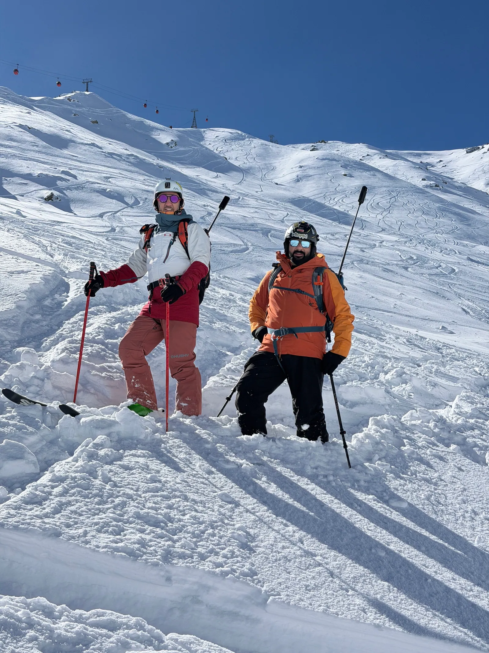 Two guided skiers posing together in deep Gulmarg powder
