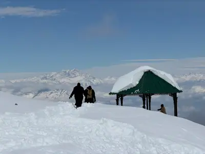 Winter trekkers approaching a snow-covered mountain gazebo