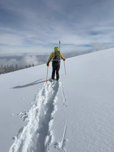 Skier skinning uphill through untouched powder