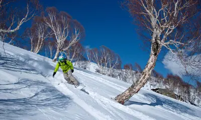 Snowboarder carving fresh powder under blue skies