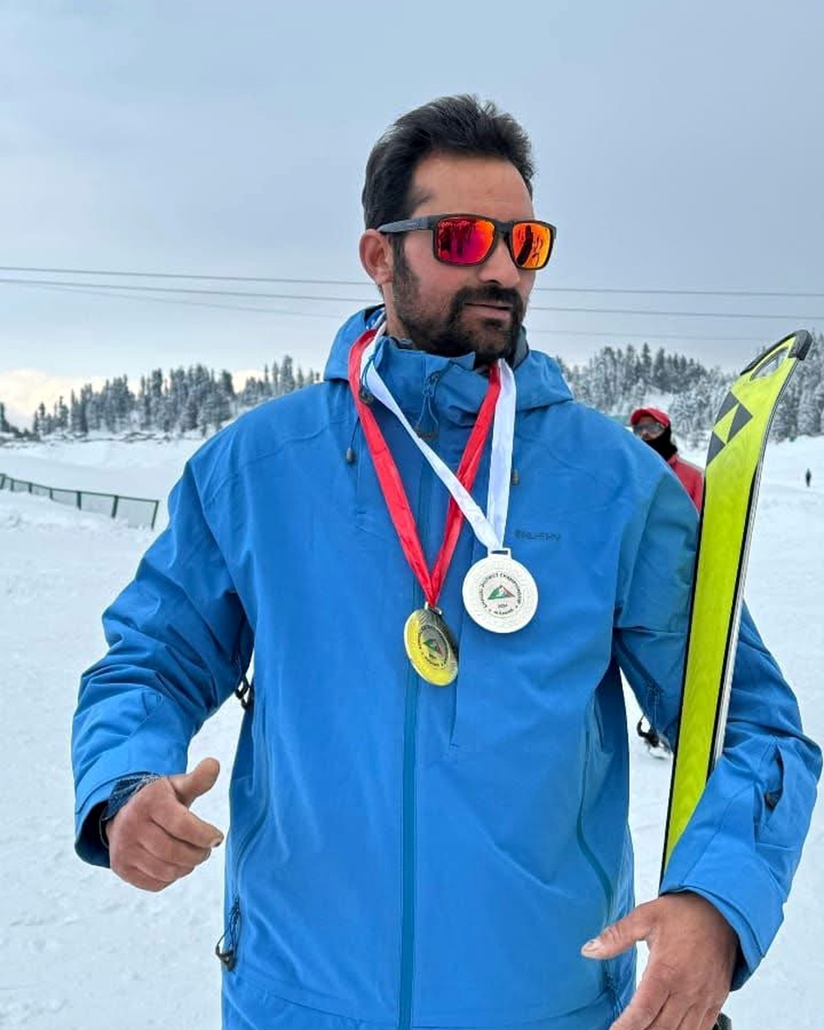 Gullu, mountain ski guide, in a blue jacket with medals on a snowy slope